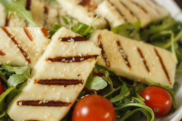 Traditional greek fried halloumi cheese on a white plate with herbs and cherry tomatoes. View from above.