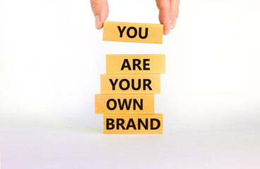 You are your own brand symbol. Wooden blocks with words You are your own brand. Beautiful white background, copy space. Businessman hand. Business, you are your own brand concept.