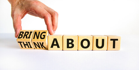 Think or bring about symbol. Businessman turns wooden cubes and changes words think about to bring about. Beautiful white table, white background, copy space. Business, think or bring about concept.