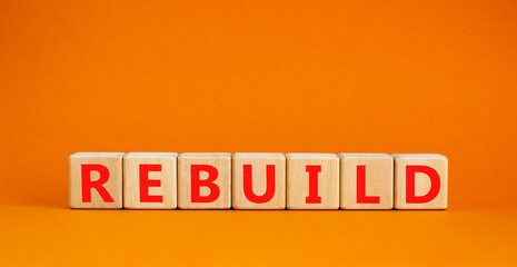 Rebuild and build symbol. The concept word Rebuild on wooden cubes. Beautiful orange table, orange background, copy space. Business rebuild and build concept.