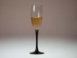 The glass filled with honey-colored wine on an illuminated light beige background