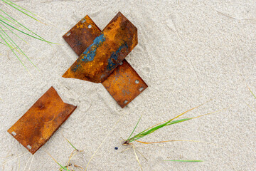A letter made of rusty metal plates on the sand.