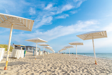 Wooden white umbrellas from the sun on the sandy beach.