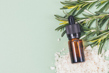 Rosemary essential oil bottle next to fresh branches of rosemary