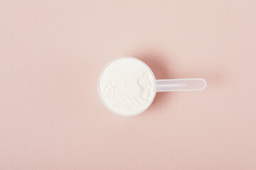 Measuring spoon with protein powder on beige background