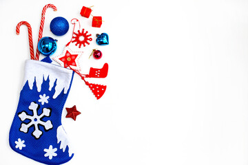 Christmas sock with red and blue Christmas toys and gifts on a white background. Top view, copy space