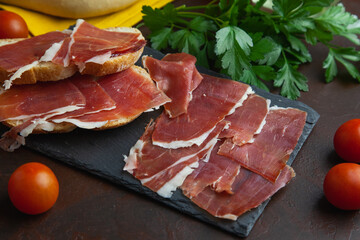Aperitivo de jamón serrano con pan tostado y algunos tomates Cherry
