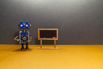 Robot teacher mentor stands near a black chalk board. Toy mechanical bot and artificial...