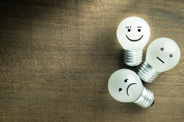 Satisfaction light bulb on wood background, excellent or happy smile face icon is glowing, with...