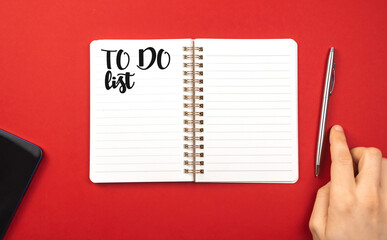 Notebook with to do list. Planning for new year concept. Red background, silver pen, copy space and top view photo
