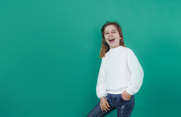 a small, beautiful girl screams loudly with her mouth wide open on a green isolated background.