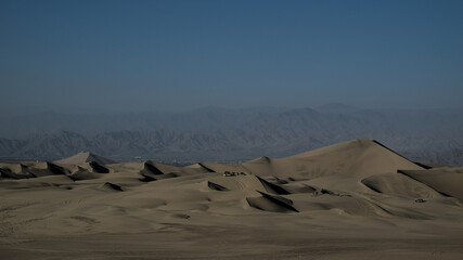 Sand dunes at the desert oasis of huacachina tourists take pictures and ride drive dune buggy sand board with guides before staying the night.