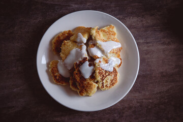 Homemade pancakes with sour cream on a wooden background