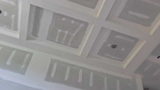 Finishing plastering drywall in ready for paint with new house under construction