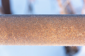 The metal pipe is covered with frost. The pipe is in the cold.