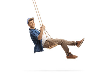 Side shot of a casual guy swinging on a wooden swing - obrazy, fototapety, plakaty