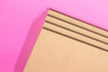 Four planks of raw MDF on a pink background.