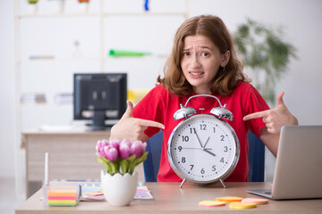 Young female designer in time management concept
