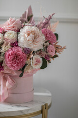 Beautiful composition with pink, white flowers and eucalyptus. Beautiful bouquet of pink roses in a festive round box on a gray background.