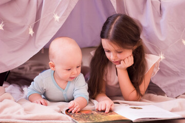 Older sister reading a book to little brother.