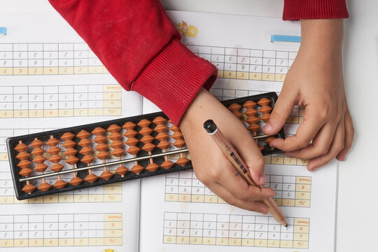 Doing mental math or mental arithmetic. Hand of little boy using abacus for calculating. Learning to use abacus on mental math courses. A kid doing math at home with abacus