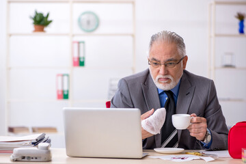 Old male employee cutting his hand in the office