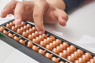 Doing mental math or mental arithmetic. Hand of little boy using abacus for calculating. Learning to use abacus on mental math courses. A kid doing math at home with abacus