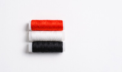 multi-colored spools of thread for sewing, folded in the form of the flag of Egypt on a white background. There is a free empty space.