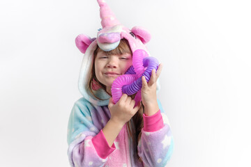 Cheerful little girl in unicorn pajamas plays in a popular toy poptube. An exciting children's game with multi-colored plastic pipes.