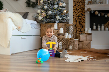 Fototapeta premium A little boy is playing on the floor in a warm sweater and pants