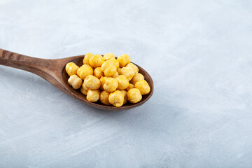 Roasted Chickpea or Leblebi  in wooden spoon, close-up. Selective focus, grey  background, copy space. Turkish healthy snack