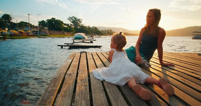 Family on the pier. Woman walks with her kid on the pier at sunset and enjoys the moments together