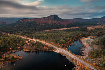 Panorama landscape with road along lake and mountains in Stora Sjöfallet National Park in autumn in Lapland in Sweden from above, clouds in blue sky.
