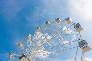 The amusement park has a Ferris wheel with closed white booths.