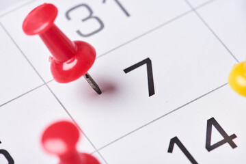 Colored push pins on monthly calendar page. Calendar appointments. Multicolored push pins on...