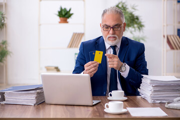 Old male employee holding credit card in the office