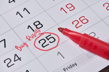 Planning Christmas costs. Writing reminder on December monthly calendar - to buy presents. 25...