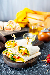 Healthy tortilla wraps viewed from side on wooden cutting board, tortilla with chicken and vegetables