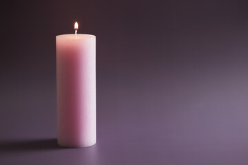 Pink candle with fire on purple background.