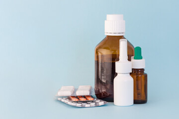 Set of medicine, nasal spray, syrup, drops, vitamines on blue background.