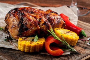 A whole young chicken baked in the oven and served with vegetables on a wooden board.