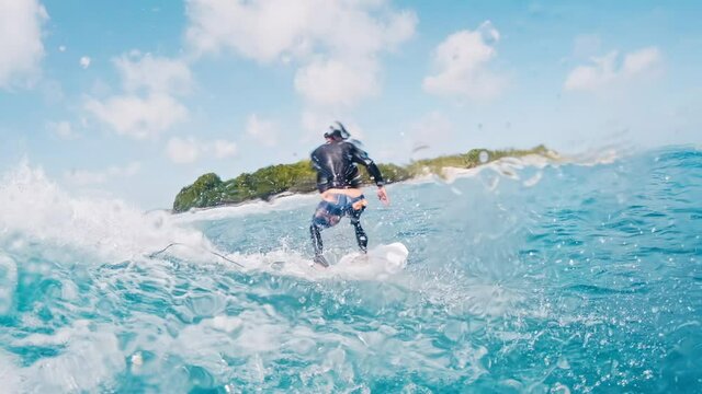 Male surfer rides the wave. Man surfs the perfect blue wave in Maldives