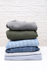 Vertical image of folded stacked warm winter and autumn casual clothes close up