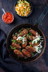 Traditional Croatian cevapcici spicy meat ball rolls with cabbage carrot salad and hot ajvar sauce served as top view in a rustic skillet