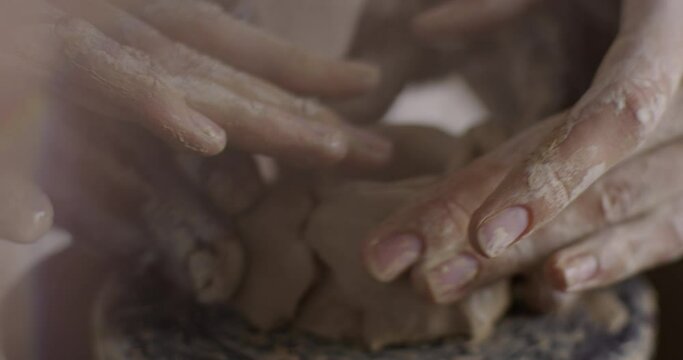 beautiful hands of an African man and a Caucasian woman sculpt from clay a cup in the machine. Close-up