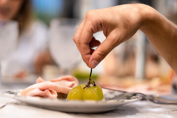 Hands picking a grape from the breakfast plate