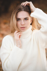 Attractive blonde in a white sweater on a background of autumn colors