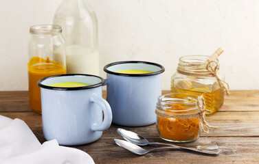 Two cups of golden milk, turmeric beverage and ingredients