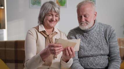 nostalgia, happy elderly family couple enjoy memories, gray-haired man and woman looking at old album with photos at home