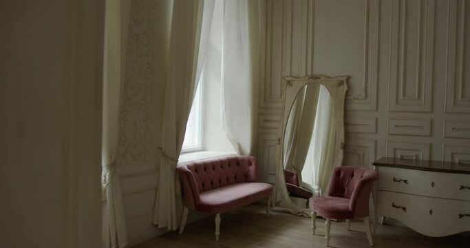 a beautiful Provence style room with a pink sofa and a chair and a large cream mirror. two windows with curtains and a large column. zooms in front of the camera. interior in Paris. Overall plan